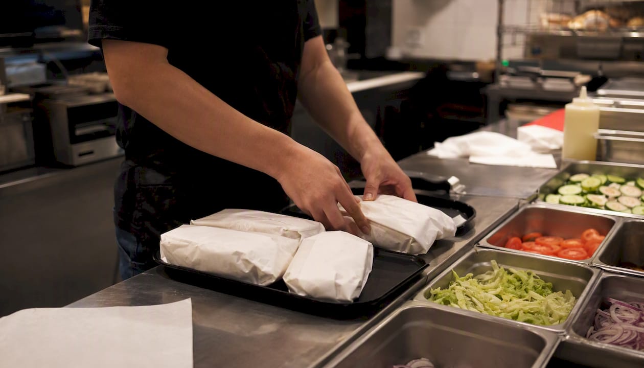 Hands assembling sandwiches quickly in fast food kitchen