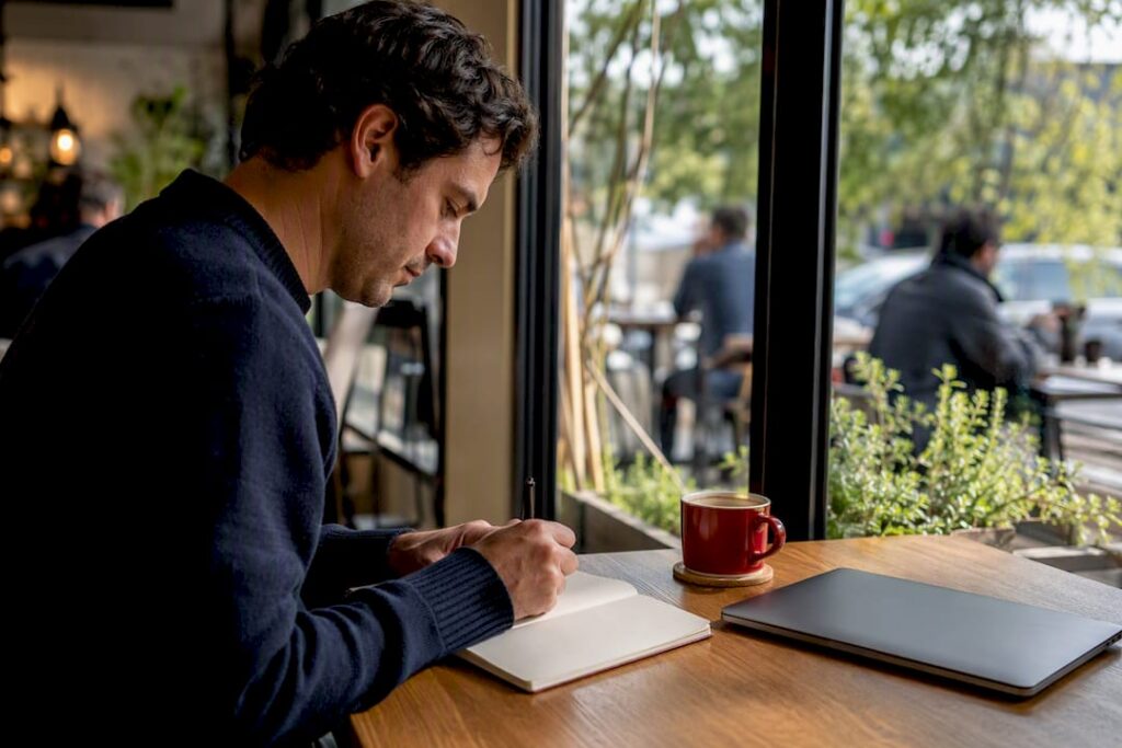 Analyst taking notes at desk with coffee